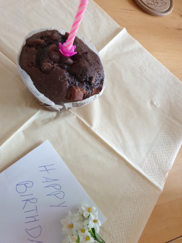 Schokomuffin mit einer Kerze und ein Happy Birthday Briefchen