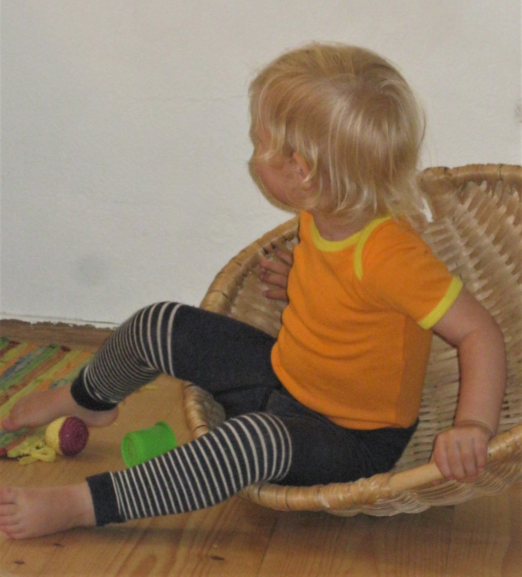 Kleinkind sitzt in einem runden Korb und schaukelt
