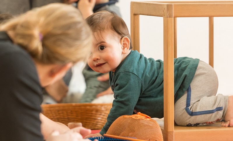 Baby krabbelt aus dem Pikler-Tunnel und freut sich