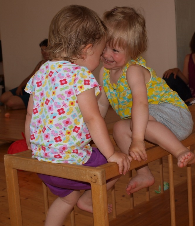 Zwei Kleinkinder treffen sich im Pikler-Tunnel und lächeln sich freudig zu