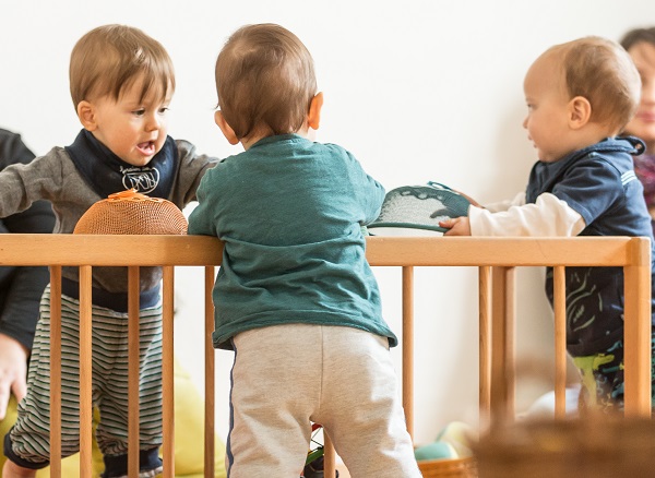 3 Babys stehen am Pikler-Tunnel und spielen