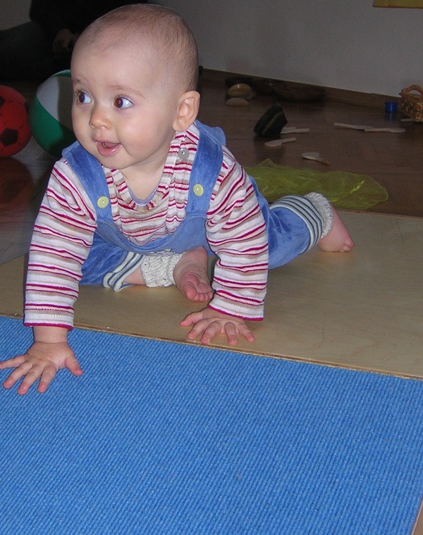 Baby sitzt auf einem Podest mit schiefer Ebene