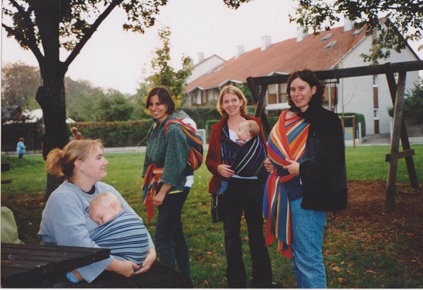 Eine Gruppe von Müttern mit Babys im Tragetuch auf einem Spielplatz