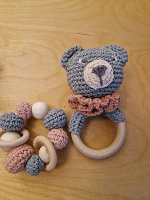 gehäkelte Greiflinge - ein Ring aus bunten Häkelbällchen und Holzperlen sowie Holzringen und ein Bärchen auf einem Beißring