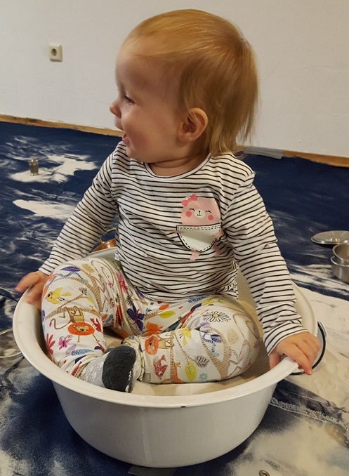 Baby stützt sich auf Podest und steht auf