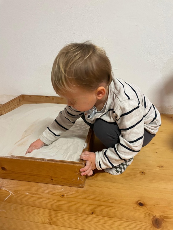 SandSpielRaum Kaisersdorf - Kleinkind wühlt im weißen Sand