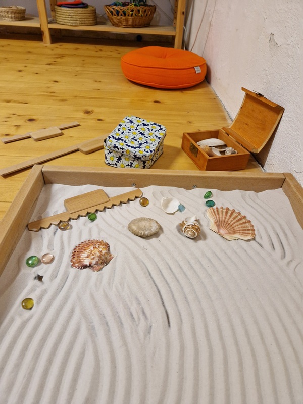 Glaswanne gefüllt mit weißem feinen Sand zum Muster ziehen, Glasperlen und Muscheln zum Dekorieren